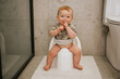© Johnér - Portrait of cute boy sitting on potty seat in bathroom