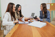 © sorapop - Busy women meet for office work, team collaborating market strategy, reviewing project documents and calculations using laptop and calculator with engaged smiles