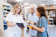 © Zoran Zeremski - Female pharmacist helps a senior man and a woman choose medication in pharmacy.