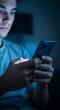© Sepnengsih - Young man engrossed in his smartphone in a dark room at night.