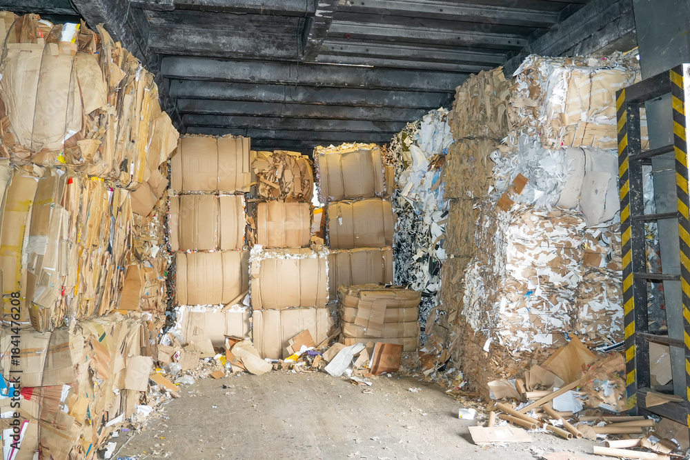Large stacks of compressed paper blocks are piled high inside a dark ...