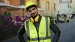 © Krakenimages.com - Young man wearing safety gear stands confidently on a terrace at an outdoor restaurant smiling with crossed arms.