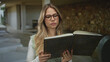 © Krakenimages.com - Woman wearing glasses holds ornate book while reading in softly lit spa room; serenity focus calm concentration.