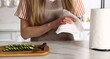 © New Africa - Woman wiping hands with paper towel at white marble table in kitchen, closeup