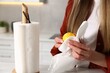 © New Africa - Woman wiping lemon with paper towel at white marble table in kitchen, closeup