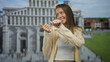 © Krakenimages.com - Woman showing thumbs pointing to the side in front of a historic building while smiling and looking sideways; playful confidence.