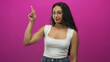 © Krakenimages.com - Woman giving a thumbs down gesture toward camera in a studio with pink backdrop wearing white tanktop and jeans; disapproval sarcasm.