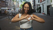 © Krakenimages.com - Woman forming heart with hands and smiling on a city street with bicycles and brick buildings; playful affection.