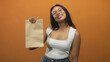 © Krakenimages.com - Woman holds brown paper bag up to camera in studio, smiling with head tilt and presenting delivery bag; promotion joy.
