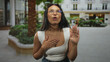 © Krakenimages.com - Woman in white tank top with hand to chest and other hand raised before a building entrance; sincerity apology.