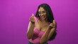 © Krakenimages.com - Woman brunette wearing glasses and pink top makes finger heart gesture with both hands and smiles, visible hands and neckline in studio; playful joy.