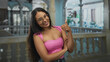© Krakenimages.com - Woman with glasses giving thumbs up and crossed arms wearing pink top in building; confidence approachability.