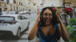 © Krakenimages.com - Young hispanic woman in blue tank top and glasses raises hands to head and shouts, cleavage visible on a busy street with cars and lampposts; spontaneous surprise.