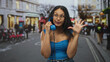 © Krakenimages.com - Woman holds blue telephone to ear with hand on hip on busy street, wearing glasses and denim; curiosity connection.