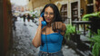 © Krakenimages.com - Young woman holding blue telephone and points fist to camera on cobblestone street; confidence empowerment.