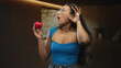 © Krakenimages.com - Young hispanic brunette woman holding small red heart with left hand and cupping right ear while mouth open in studio; surprise love wellness.