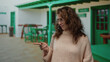 © Krakenimages.com - Woman wearing glasses and sweater pointing on a restaurant terrace with green decorations evokes a contemplative mood outdoors in the city.
