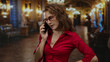 © Krakenimages.com - Woman in red shirt using smartphone inside ornate church with chandeliers, surrounded by dim lighting and elegant decor, appears focused on conversation.