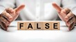 © Pixel Stone - Businessman hands hovering over wooden blocks spelling the word false concept of deception and untruth