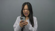 © Krakenimages.com - Chinese woman frustrated with phone isolated against grey background expressing anger and disappointment.