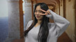 © Krakenimages.com - Young chinese woman makes peace gesture by her eye while smiling outdoors in an old town corridor.