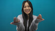 © Krakenimages.com - Young chinese woman making come here gesture isolated against blue background wall smiling and inviting with her hands in a friendly expression wearing cozy sweater
