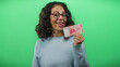 © Krakenimages.com - Middle-aged woman holding icelandic krona banknotes with a playful expression against a vibrant green wall, showcasing financial creativity and humor in an isolated setting.