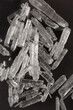 © nahhan - A pile of translucent, colorless menthol crystals is scattered on a dark, reflective surface