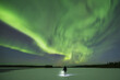 © Travel 'n' Lifestyle - View of a solitary figure standing on a snow-covered expanse, illuminated by a beam of light under the ethereal glow of the Aurora Borealis, Kuusamo, North Ostrobothnia, Finland.