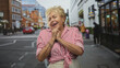 © Krakenimages.com - Woman clasping hands to chin smiling on a busy street crosswalk with storefronts and passersby; warmth nostalgia joy.