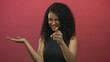 © Krakenimages.com - Young hispanic woman extends hand palm up and points finger at camera in red studio; warm invitation.
