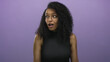 © Krakenimages.com - Young hispanic woman with curly hair and glasses looks surprised against an isolated purple background, conveying joy and excitement.