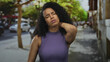 © Krakenimages.com - Woman on street experiencing neck pain wearing purple top with eyes closed and urban background.