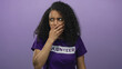 © Krakenimages.com - Woman wearing volunteer shirt, curly hair, isolated against purple background, covering mouth, expressing surprise, young hispanic female in shock, looking confused, mystified.