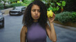 © Krakenimages.com - Woman holding yellow piggybank with disappointed expression on street surrounded by cars and greenery, conveying financial concerns outdoors.