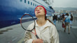 © Krakenimages.com - Woman with racket standing outdoors near a boat at a port, showcasing casual athletic style with a sense of adventure amidst a maritime backdrop.