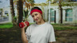 © Krakenimages.com - Woman exercising outdoors with a red dumbbell, wearing a white shirt and red headband, smiles against a backdrop of palm trees on a sunny city street.