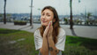 © Krakenimages.com - Young woman with tattoos praying outdoors on a city street with palms and a marina in the background, expressing hope and spirituality with closed eyes.