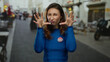 © Krakenimages.com - Woman in blue sweater with vote badge makes playful gesture on city street outdoors, emphasizing young female voter engagement in the united states.