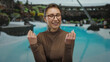 © Krakenimages.com - Woman smiling happily with glasses at a resort poolside, showcasing joyful emotions in a relaxing outdoor hotel setting under a clear sky.