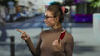 © Krakenimages.com - Young woman holding a swiss passport while pointing on a city street under sunny outdoor conditions.