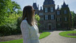 © Krakenimages.com - Woman in white dress stands smiling in front of kasteel keukenhof in the netherlands, surrounded by lush greenery and bright sunshine, highlighting the beauty of the historic castle.