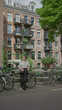 © Krakenimages.com - Woman standing by bicycles along amsterdam canals with historic buildings and lush greenery on a sunny day.