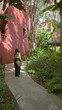 © Krakenimages.com - Woman walking on a lush tropical path at a luxury resort with red buildings, showcasing a serene vacation atmosphere.