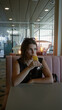 © Krakenimages.com - Young hispanic brunette woman sipping a mimosa from a champagne glass while seated in a pink restaurant booth at a table inside a building; quiet contemplation.