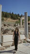 © Krakenimages.com - Woman walking and smiling while adjusting sunglasses at ancient stone building ruins in ephesus turkey; travel joy.