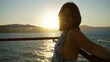 © Krakenimages.com - Woman leans on cruise rail, smiling with arms out and head tilted back on deck at sunset, sunlit profile; serenity escape.