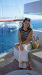 © Krakenimages.com - Woman shading forehead with hand beside woven straw bag on a ship terrace with glass railing and distant cruise building visible; serenity relaxation.