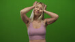© Krakenimages.com - Blonde caucasian woman raises arms above shoulder level and closes eyes in green screen studio; serenity.