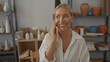 © Krakenimages.com - Woman holds smartphone to ear in art studio filled with ceramic vessels and wooden shelves; connection.
